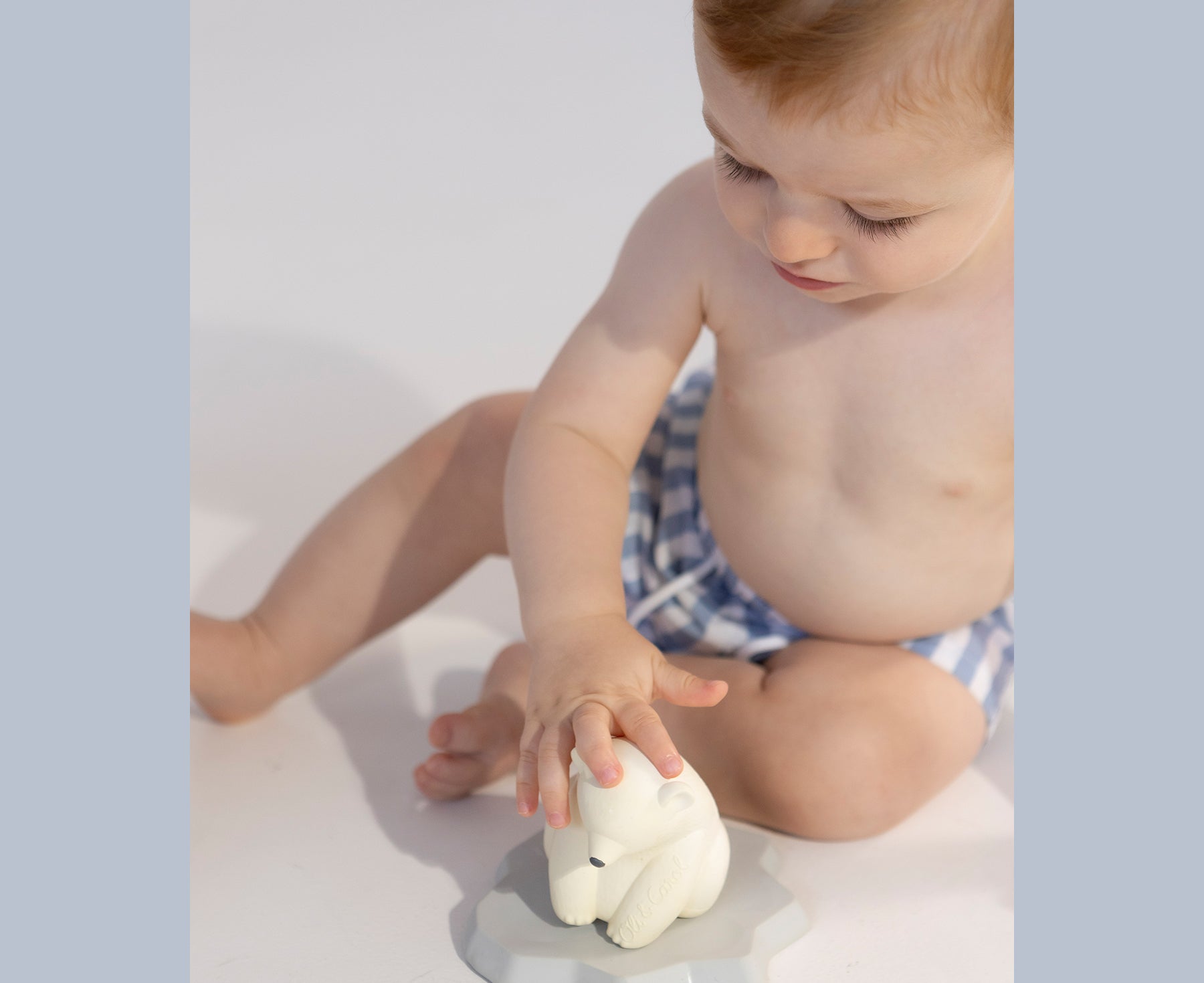 Child playing with the ice bear chewable toy with Oli & Carol branding.